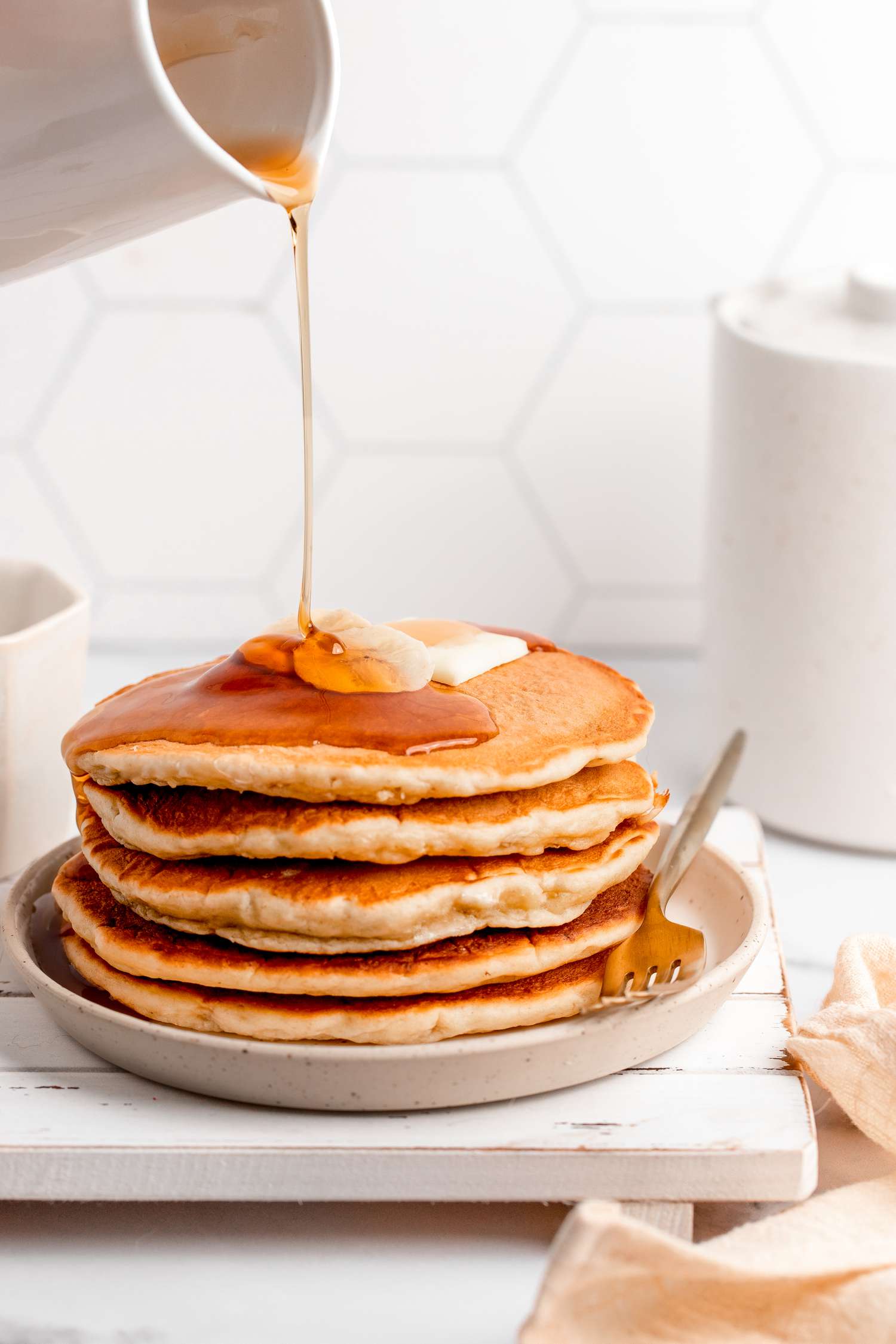 Syrup Poured onto a Stack of Banana Pancakes Topped with Butter and Banana Slices