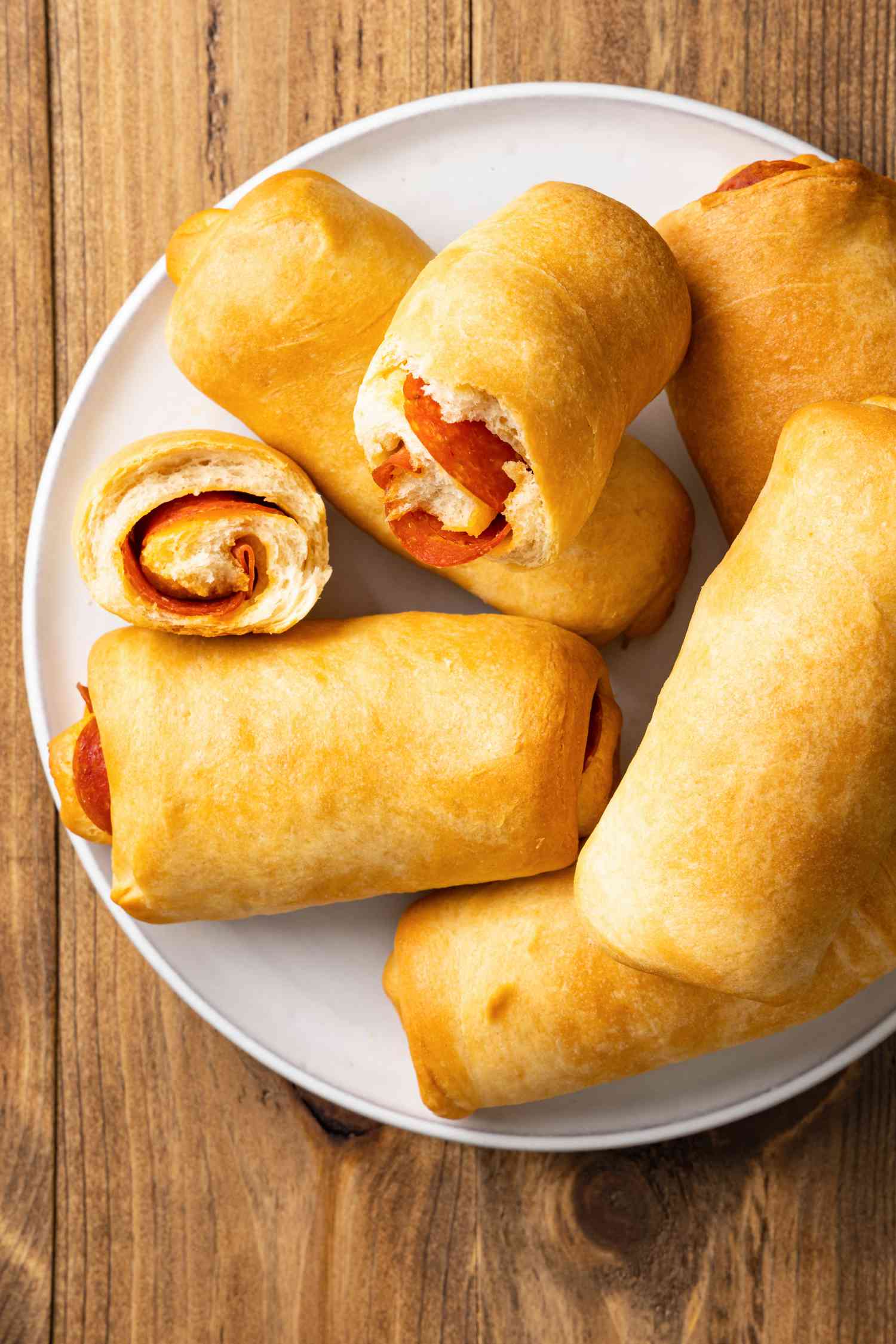Pepperoni Rolls with One Broken in Half on a Plate