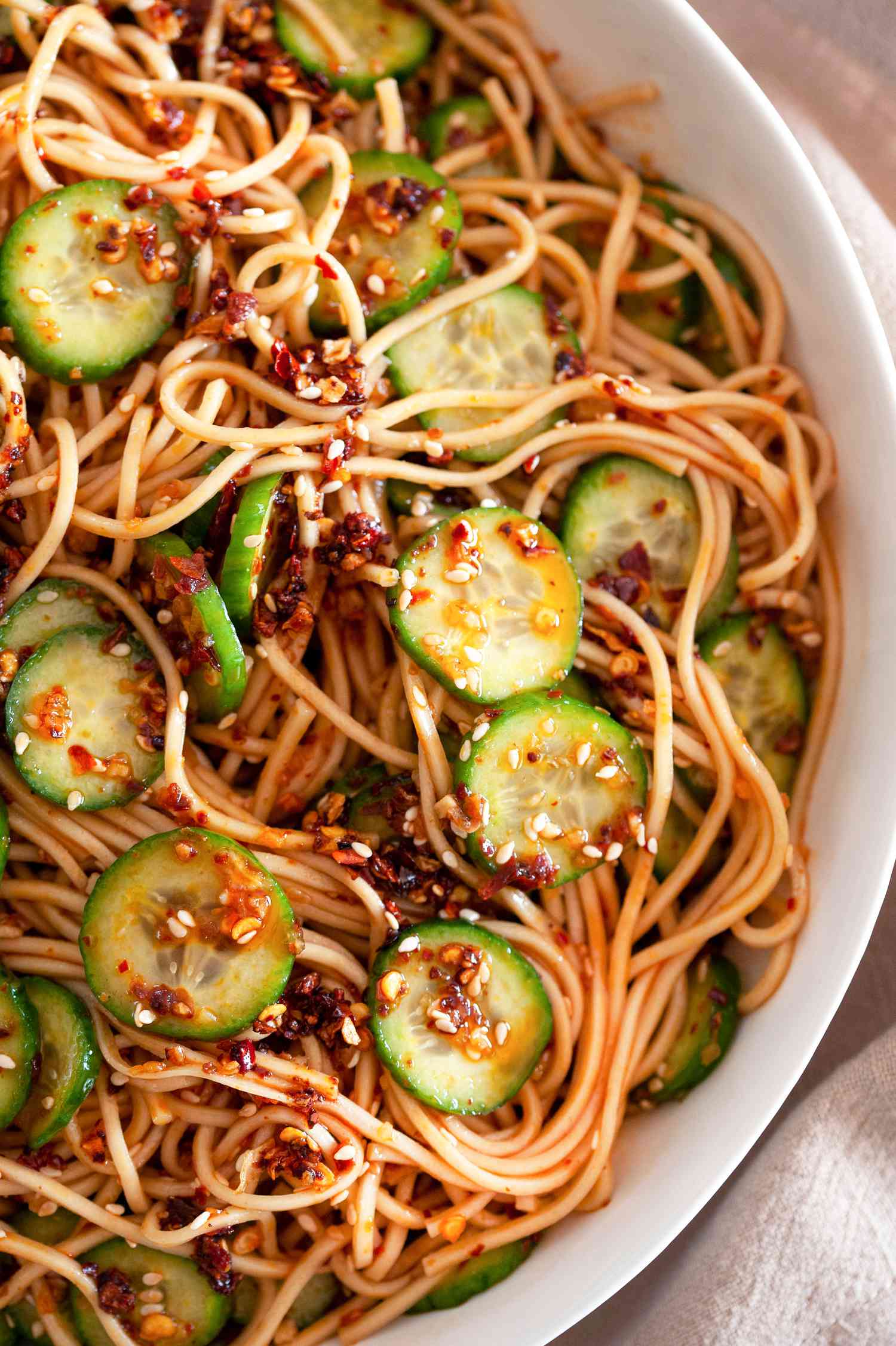 Large bowl of spicy noodles with cucumbers and chili crisp.