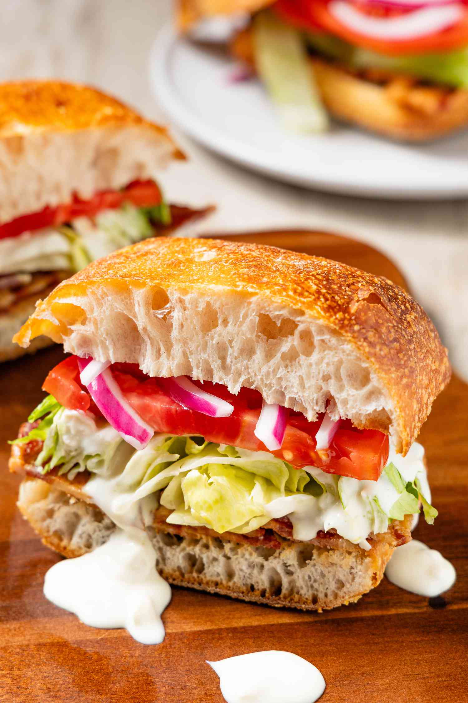Wedge Salad Sandwich Sliced in Half on a Cutting Board, Next to Another Slice on the Same Board, and in the Background, Another Sandwich on a Plate