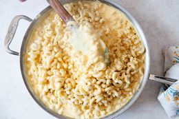 Homemade mac and cheese - macaroni noodles being stirred into a creamy cheese sauce with a wooden spatula